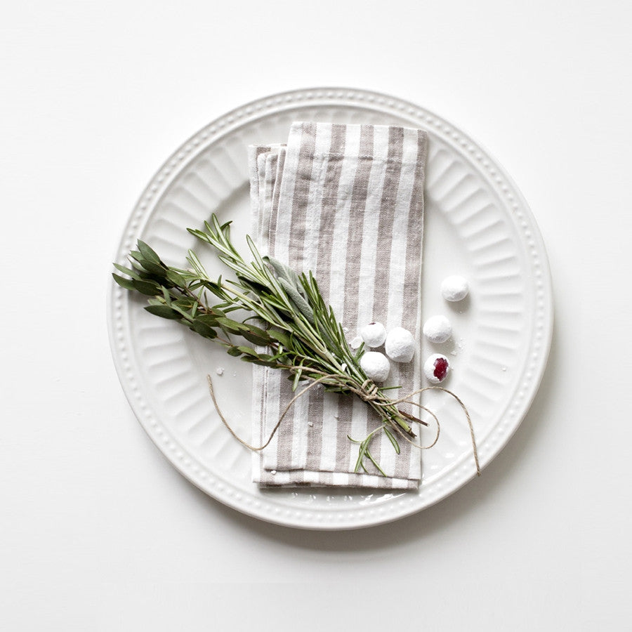 Striped linen napkin on a white dinner plate with greenery