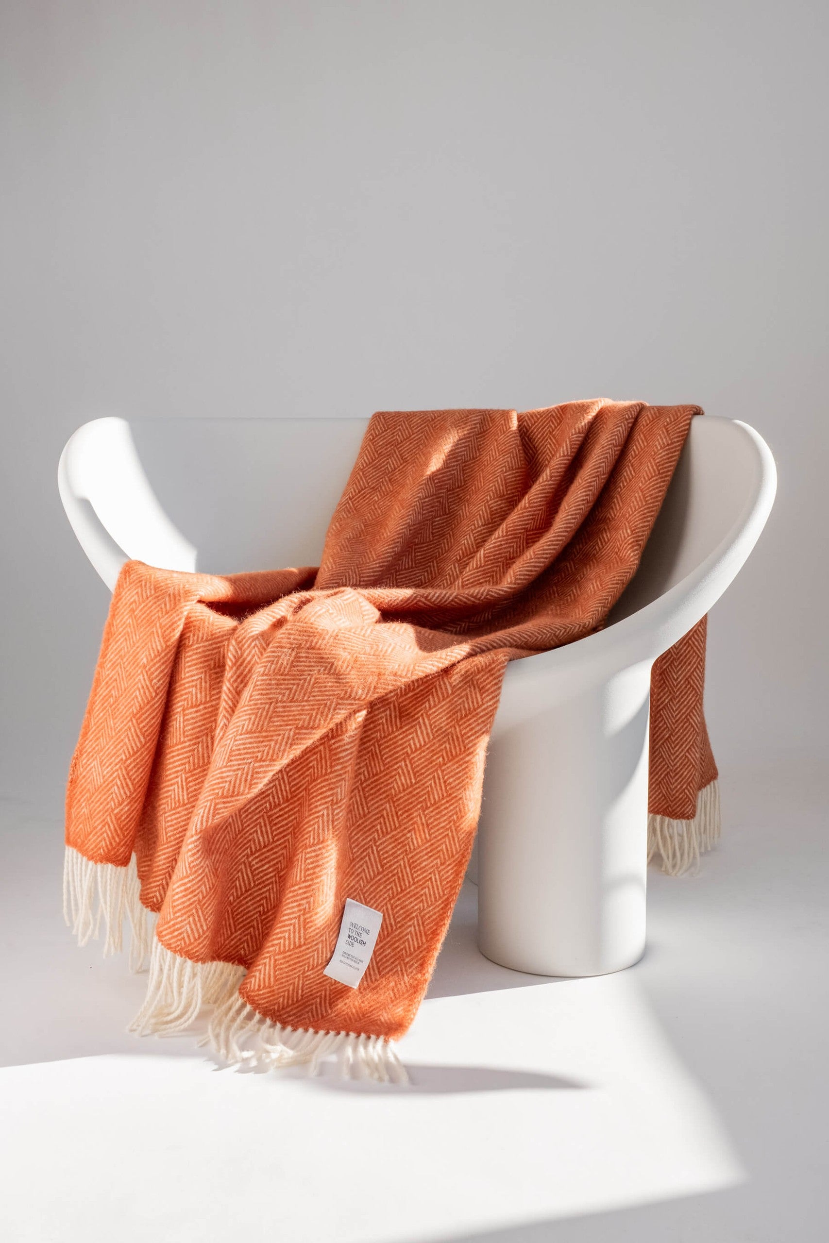 Hera pure wool throw styled on a white lounge chair