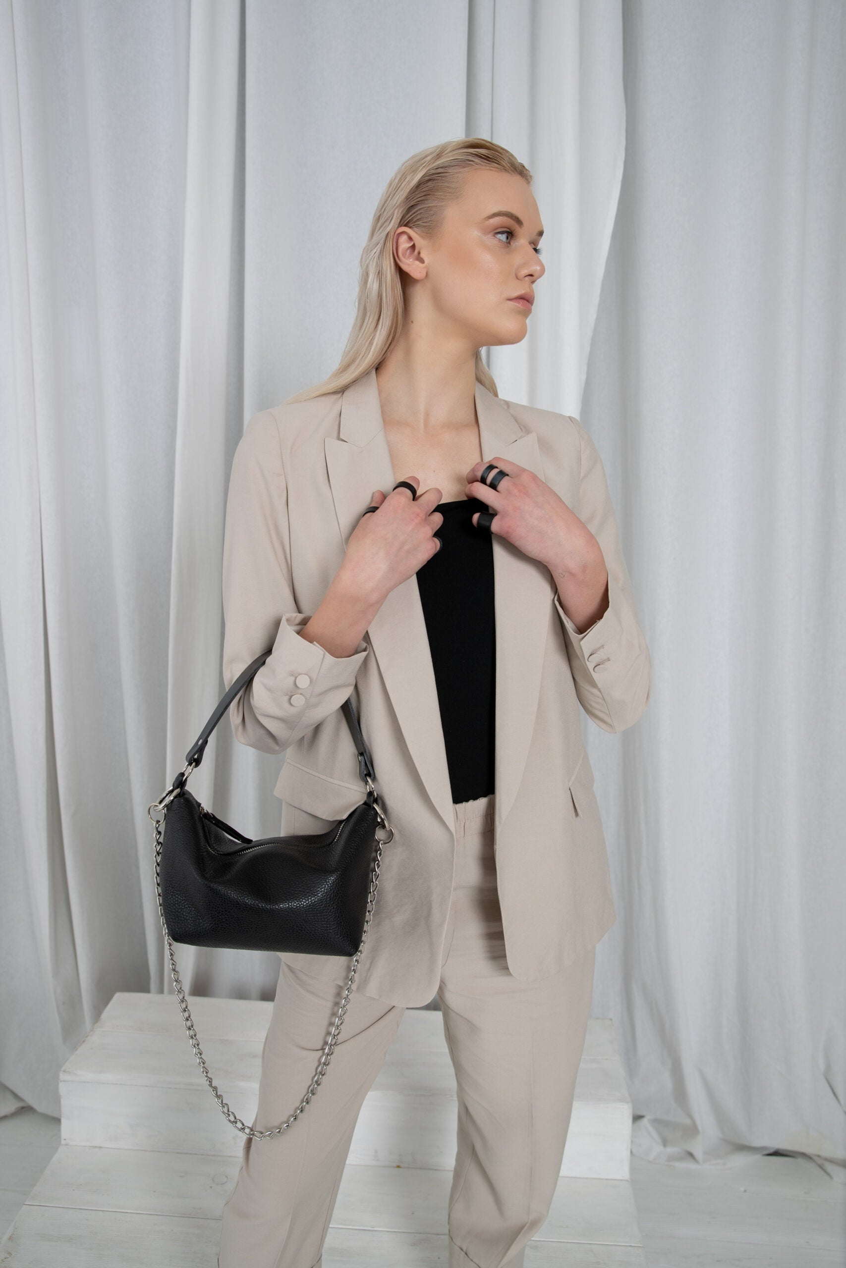 Black shoulder bag worn in a minimalist interior