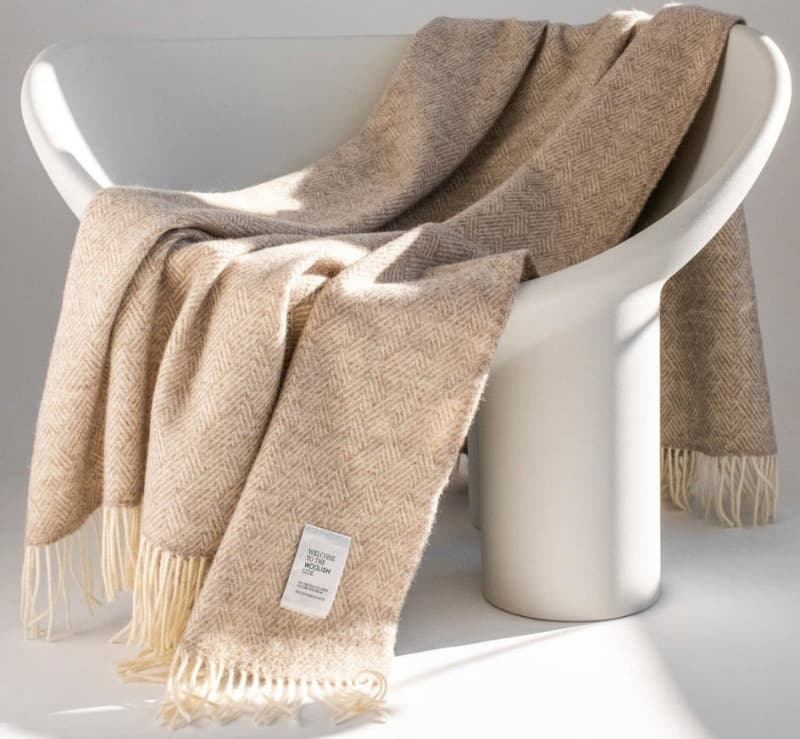 Hera Pure beige herringbone wool throw draped over a white armchair