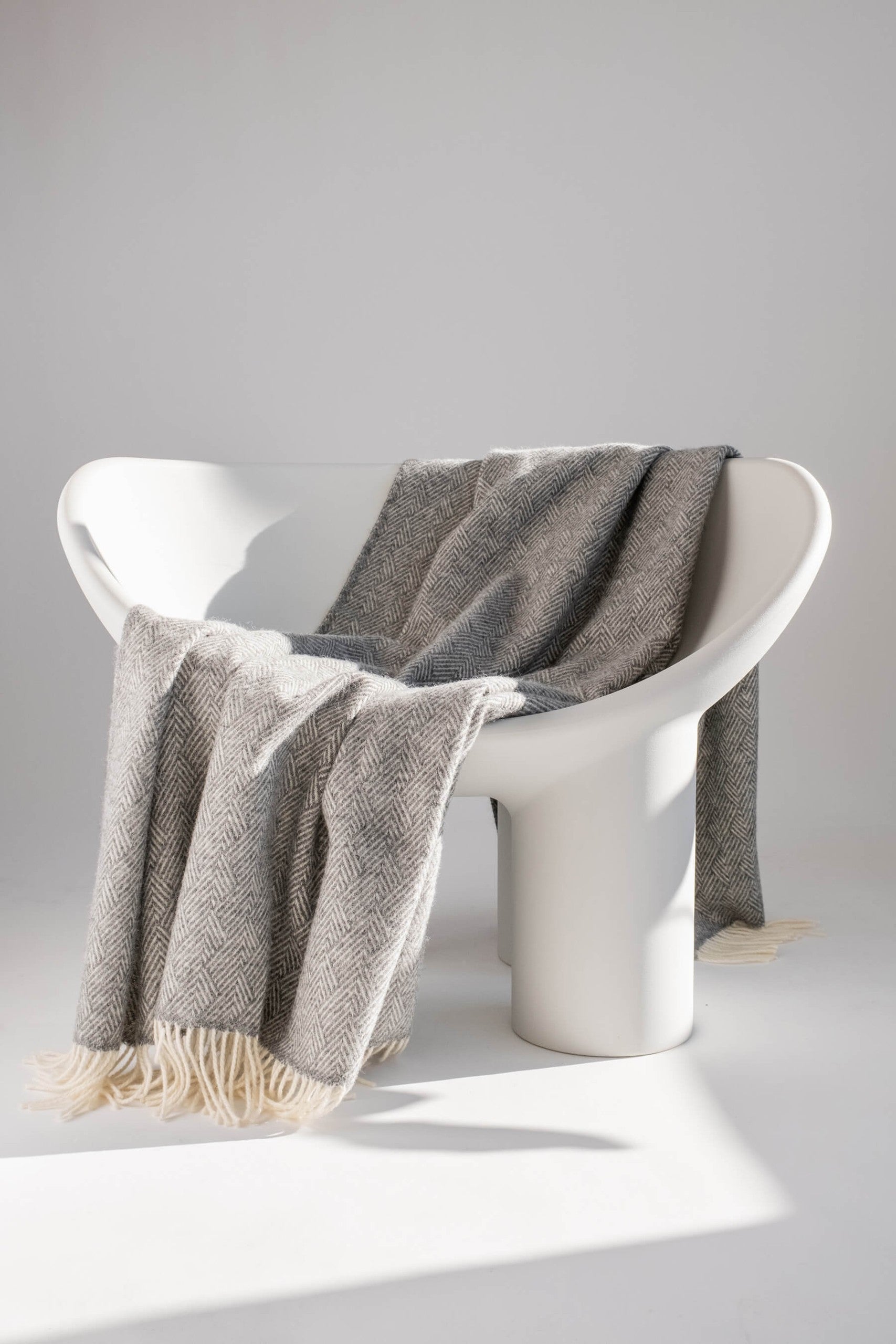 Hera pure wool throw 130 x 170 cm draped over a white chair