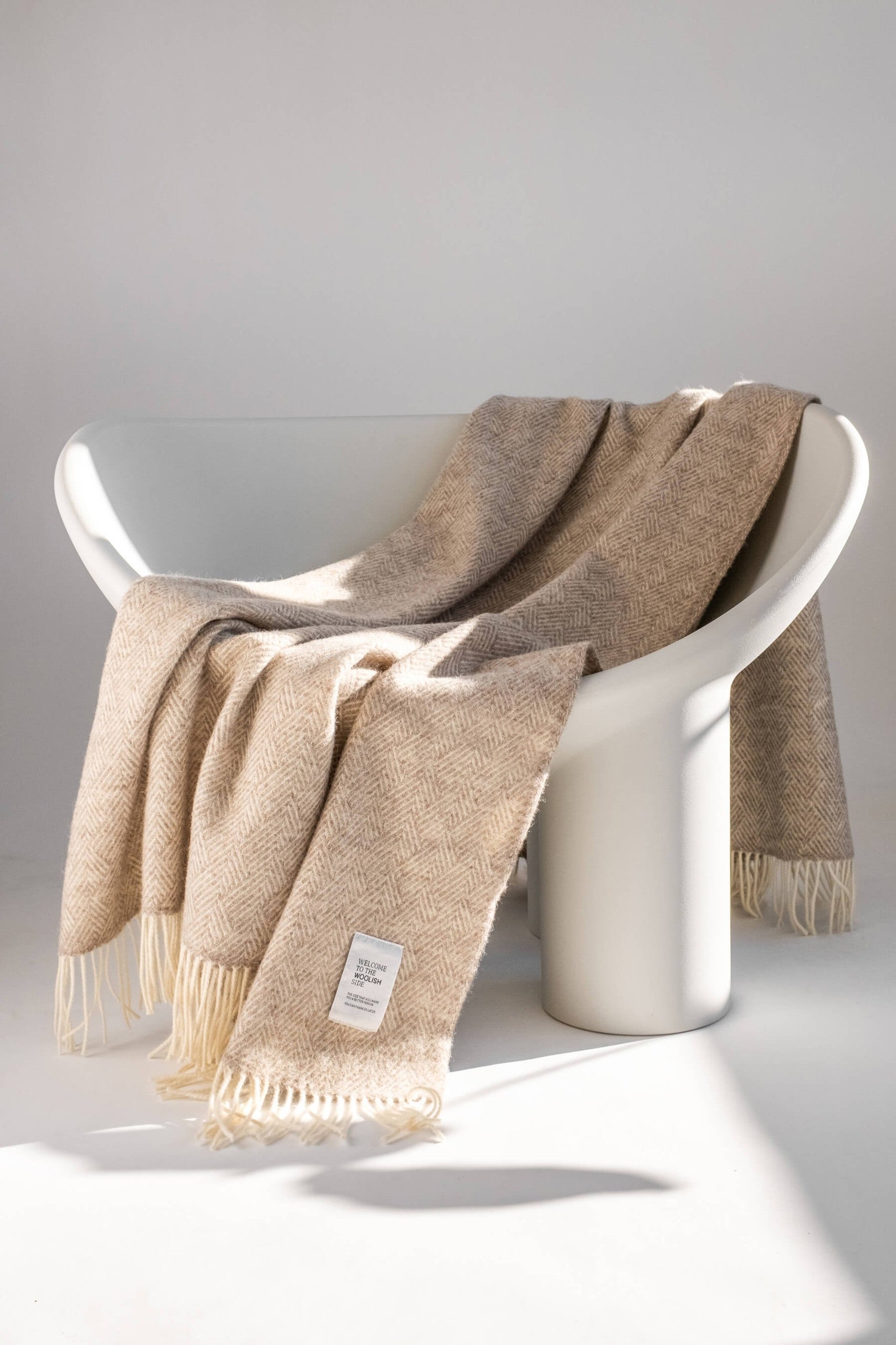 Hera pure wool throw styled on a white lounge chair